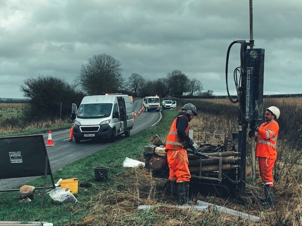 Two workman drilling into ground for testing